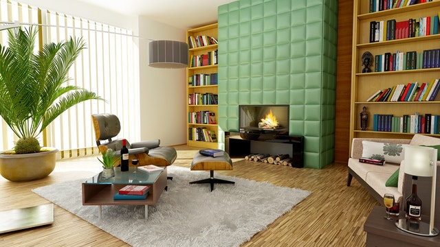Priestranná izba s tyrkysovým obkladom nad kozubom, huňatý koberec, kreslo, palma a veľké police na stenách